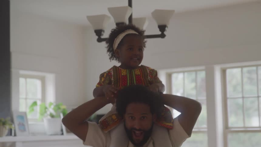 Father jumping while carrying his daughter on his shoulders