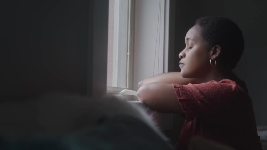 Woman facing a window closing her eyes