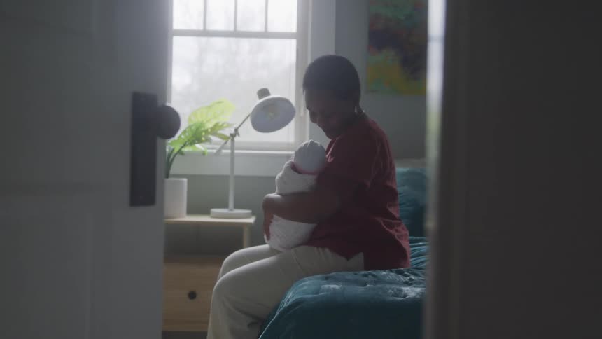 Mother sitting with a newborn baby on her lap in a room