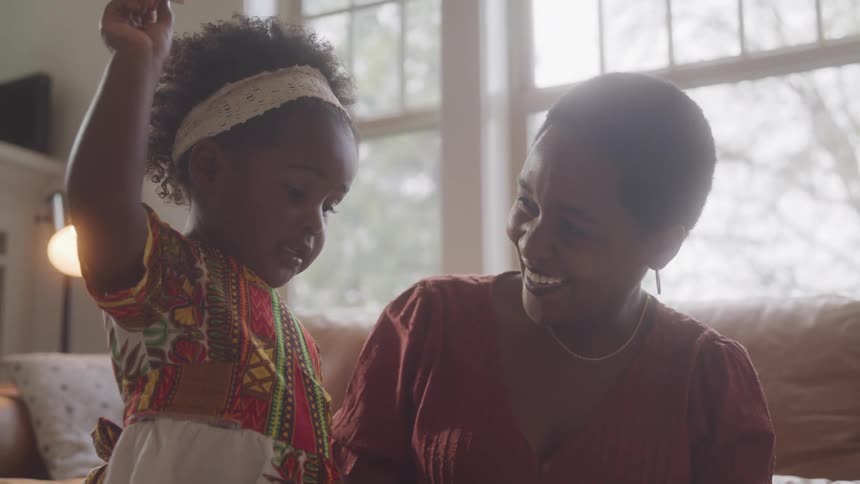 A woman next to a little girl who is playing and the woman is happy