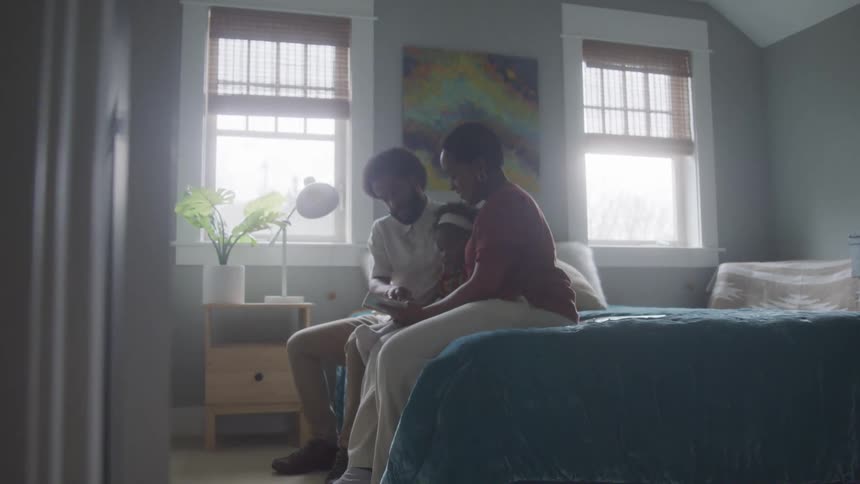 A family are looking at a book while sitting on the bed