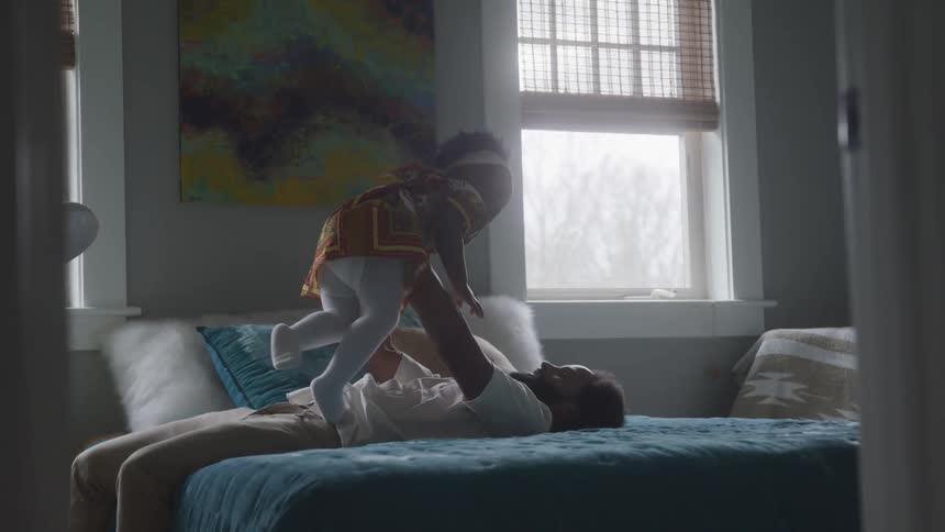 A father lifts up his daughter on the bed