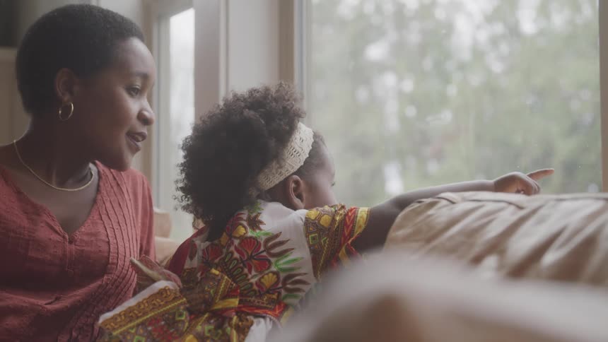 Woman sitting with her daughter looking out the living room window