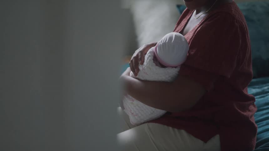 Woman sitting on bed holding a baby in her lap