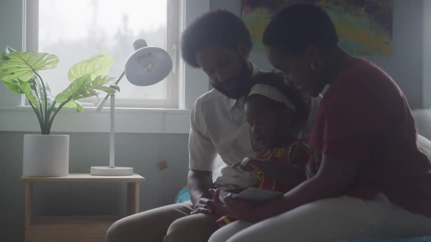 A mother and father are reading to their daughter