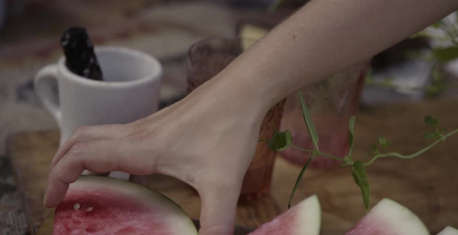 Woman picking up and handing another woman a slice of watermelon