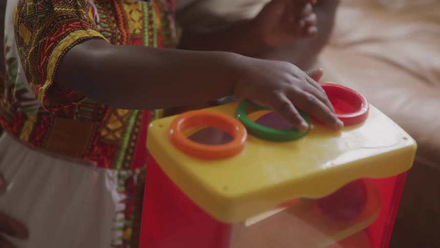 Close up of a girl wearing a colorful dress is playing with a toy in a room
