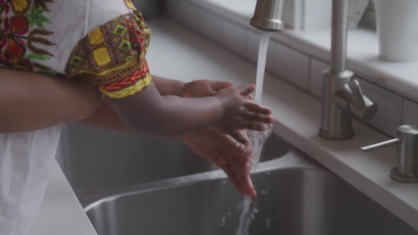 A child is being helped with cleaning her hands