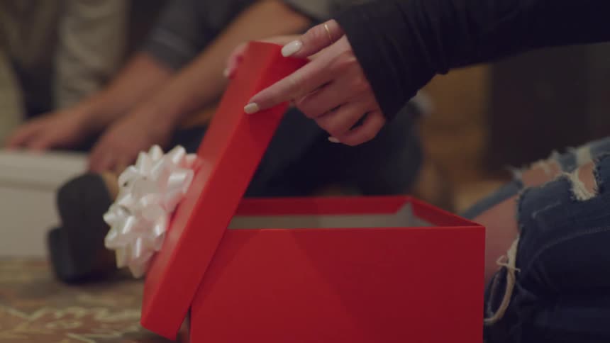 Opening a gift in a red box with a white bow