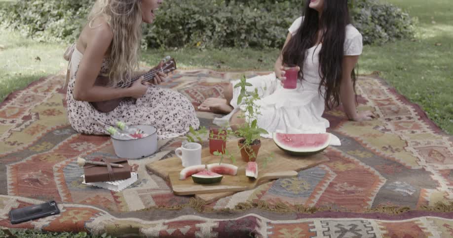 Two women are laughing and having a picnic during the day