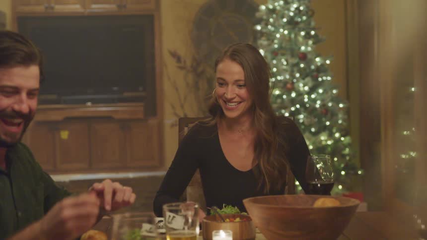 People sitting at a dinner table at night happily serving themselves food