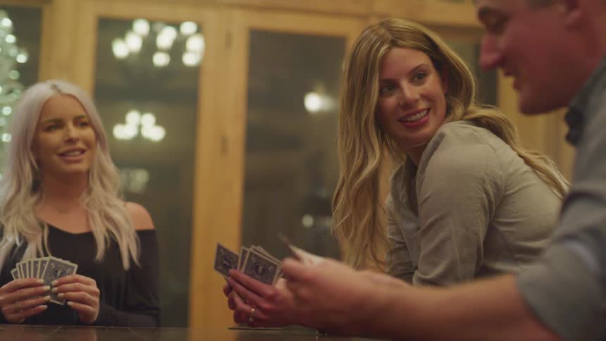 Friends sitting in the living room playing cards