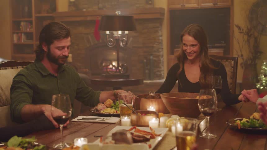 People sitting around a dinner table with candles holding hands to begin a prayer