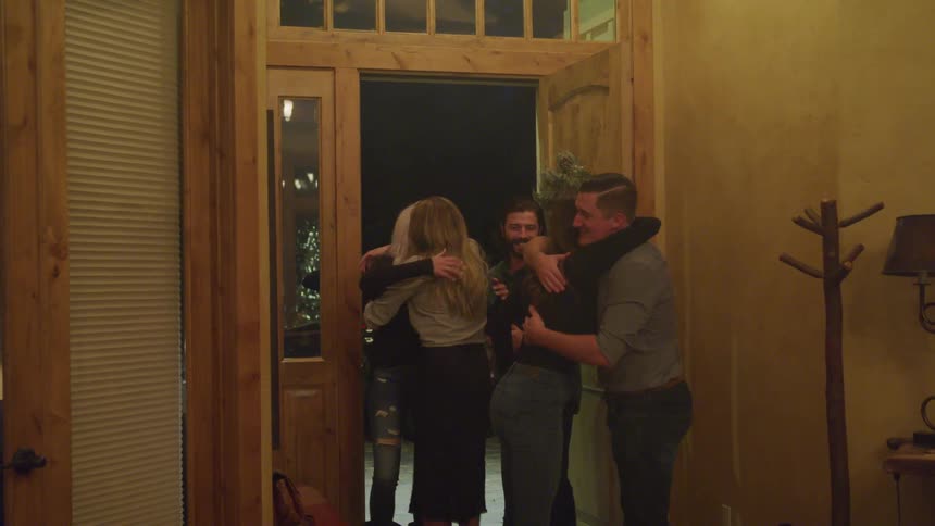 Friends happily greeting each other at front door for a get together