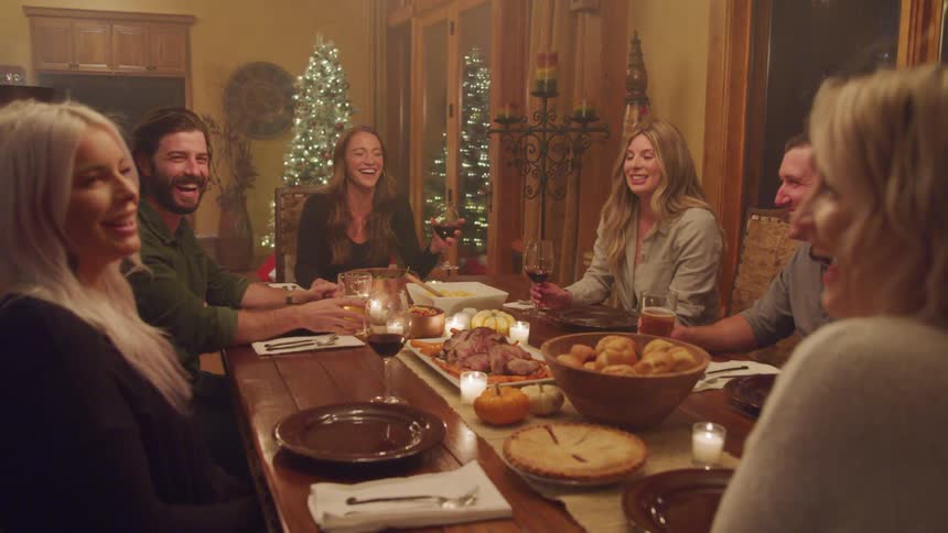 Friends gathered around dining table laughing talking and drinking