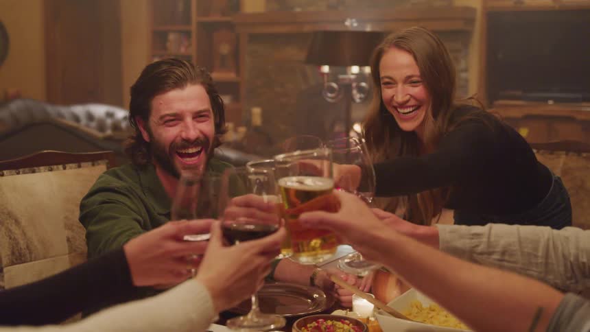 Friends toasting with alcohol gathered at table during the holidays