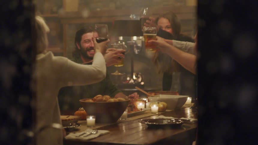 On a snowy day four people sit at a table happily toasting the evening