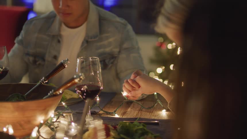 People sitting at a table with their hands together praying