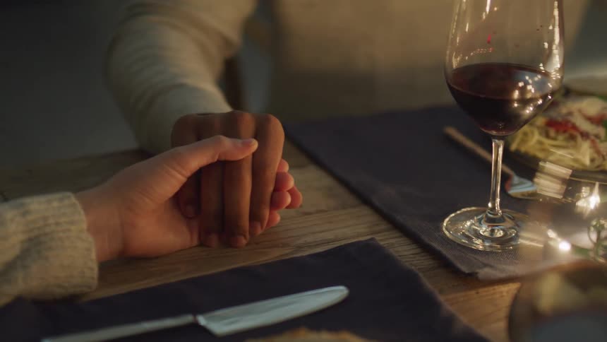 Two people holding hands praying before starting dinner
