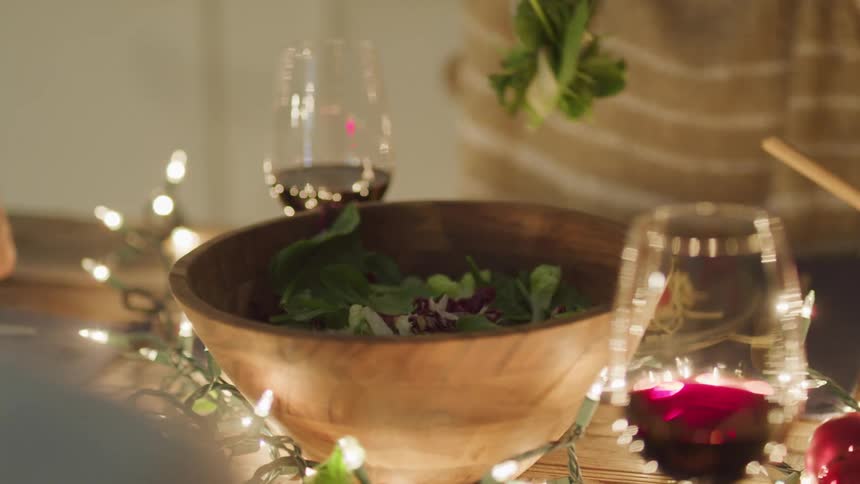 Person with a fork and spoon serving salad on their plate