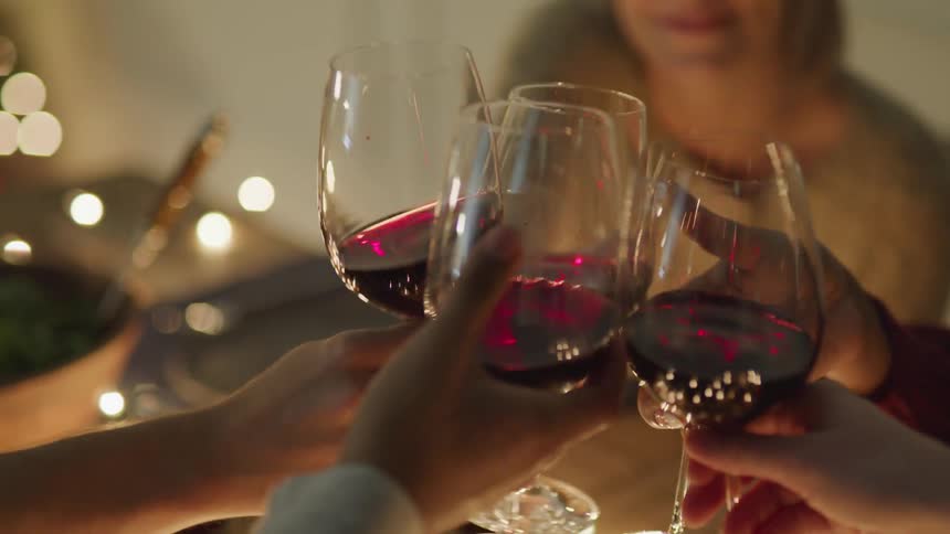 People at a dinner table toasting glasses of red wine