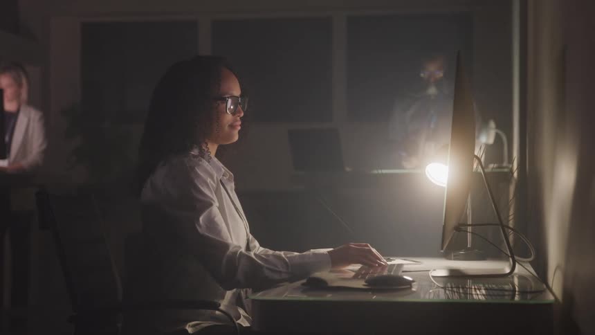 People working in a dark room sitting in front of the computer