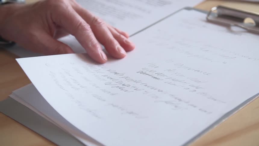 Person writing on a clipboard