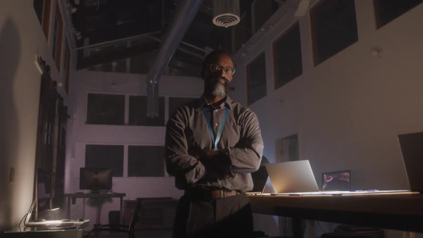 A man is standing in the dark office at night