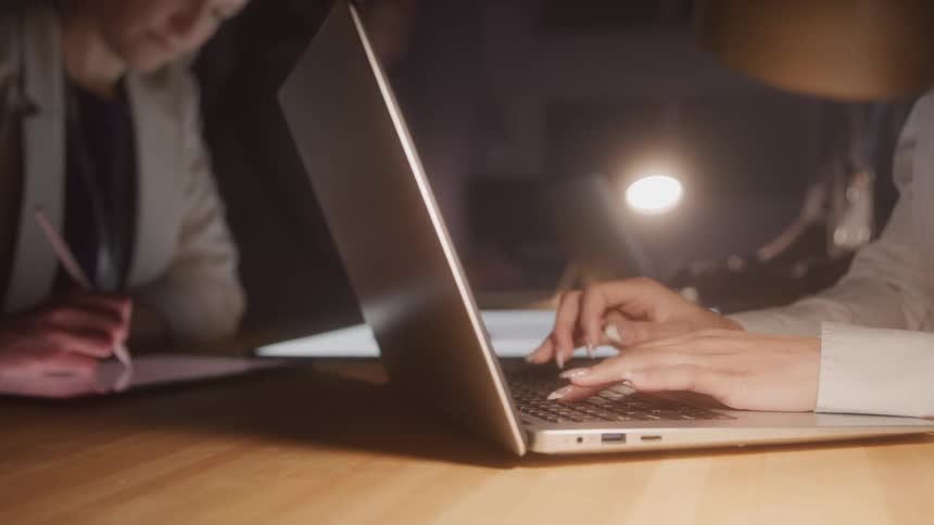 People at a table interacting with tablet and laptop