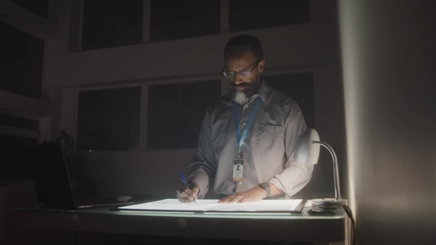Man working in a dark room with a digital screen on a table