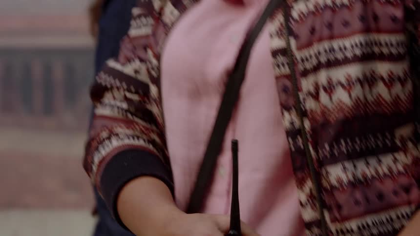 A person adjusts a walkie talkie and clips it to their pants