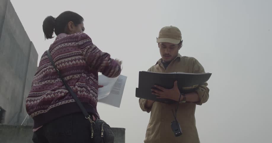 Man and woman with papers taking notes in an outdoor setting on a cloudy day