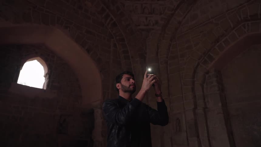 Man taking a picture with a smartphone in an indoor space of medieval architecture