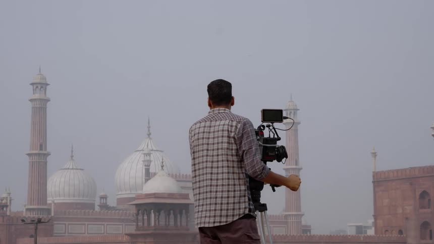 Camera operator films a landmark building on a foggy day
