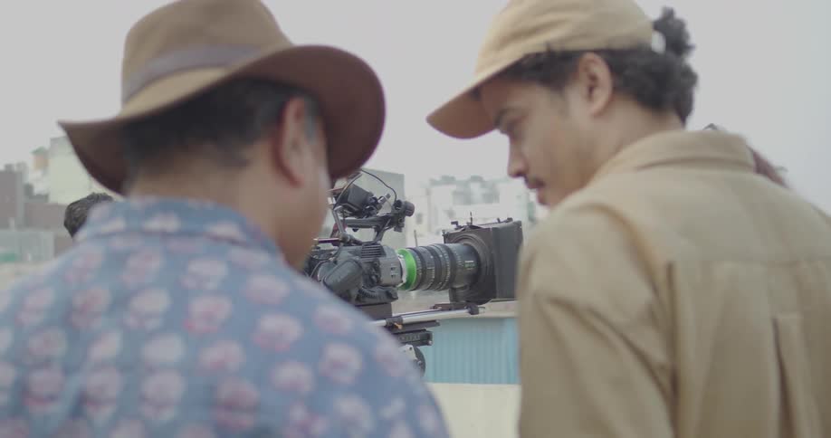 A group of men are talking near a camera outside