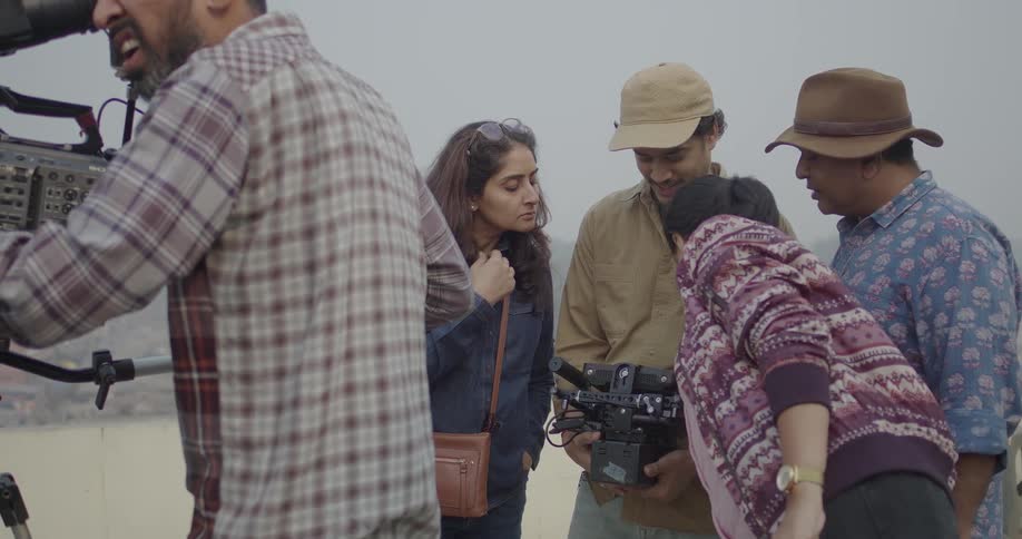 People review the video taken by camera operators while standing outdoors during the day