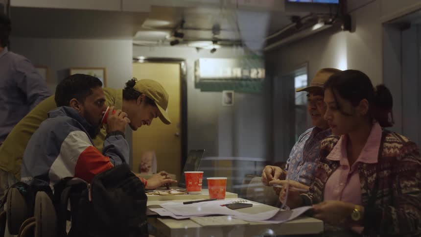 A group of people seated on a small table at a restaurant working together