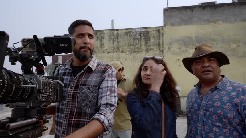 A film crew including a cameraman and an assistant director working on location with professional camera equipment