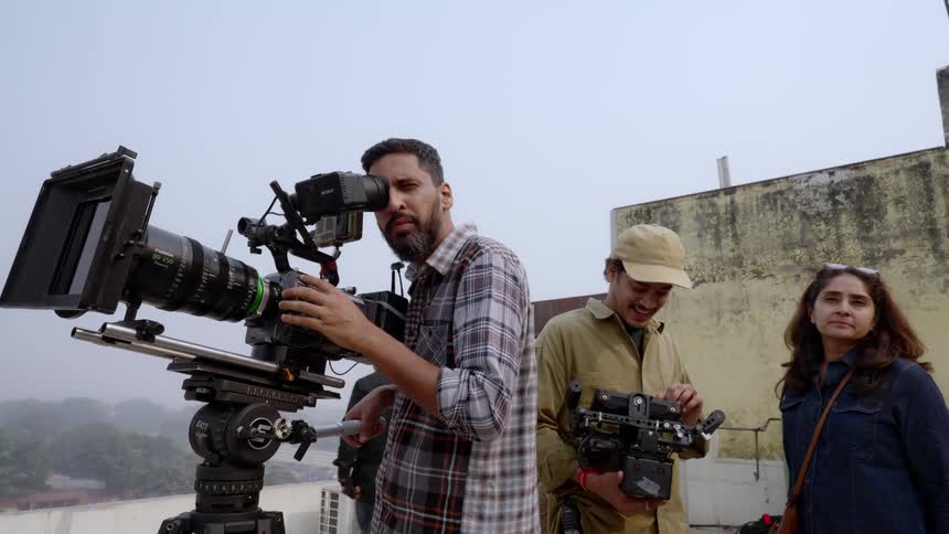 A film crew are filming on a roof