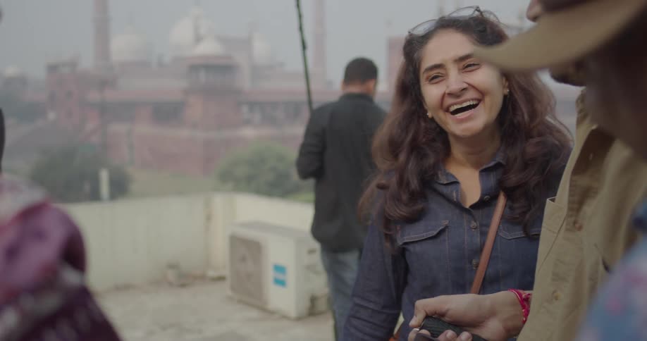 Cameraman standing on a rooftop on a foggy day shares the video on his camera with laughing friends