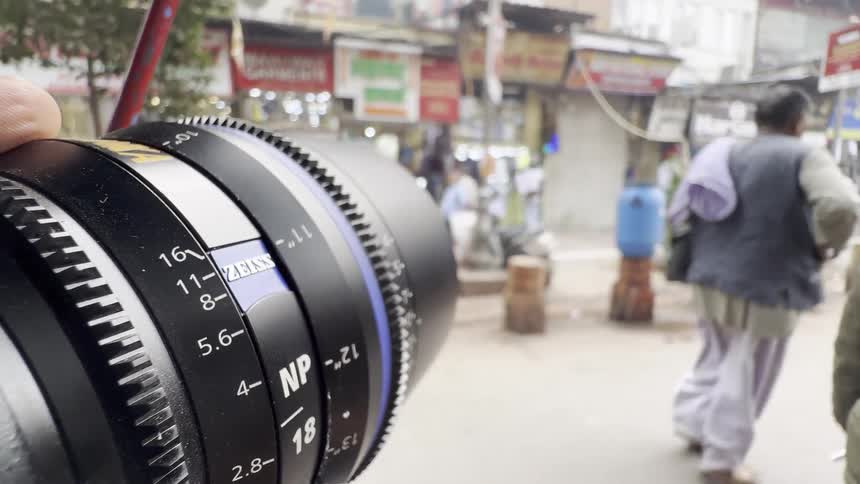 A close up of the lens of a camera mounted on a vehicle filming a busy city street