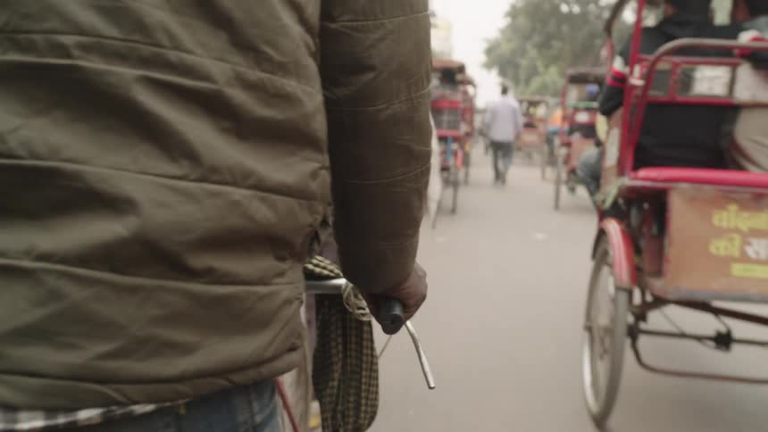 A bustling indian street teems with pedestrians and rickshaws navigating the busy road
