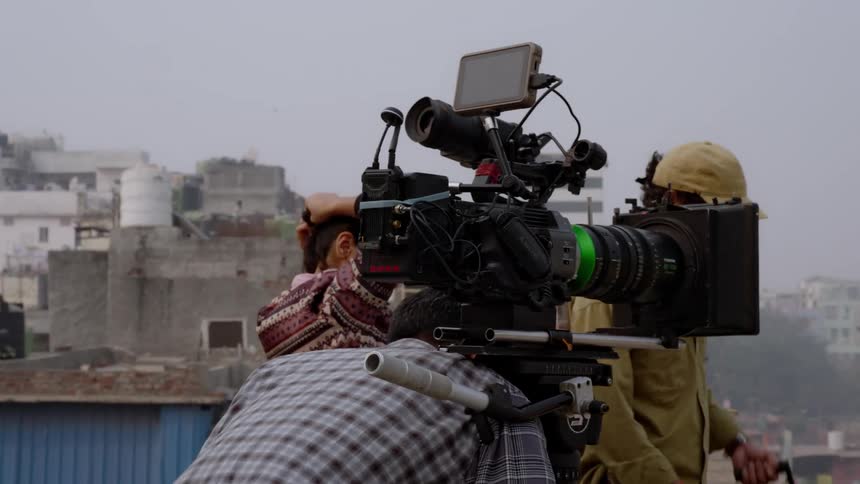 Film crew watches a camera operator place a camera during a foggy day in town
