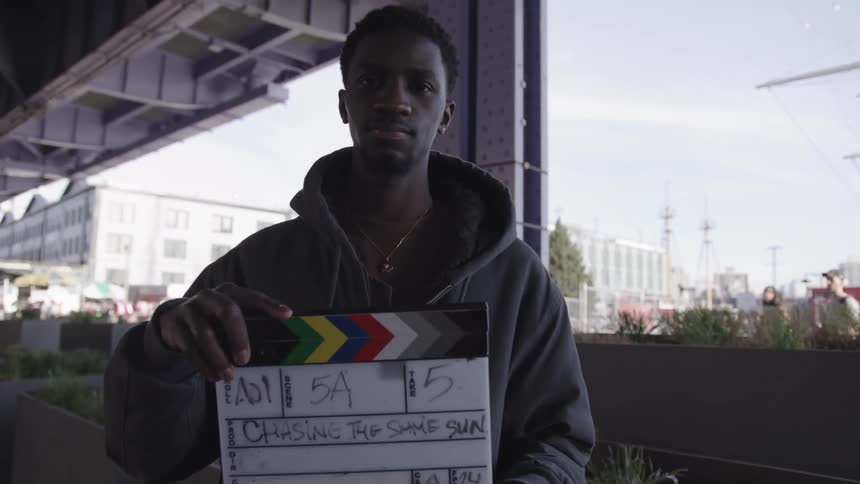 Film crew member holding a clapperboard during filming