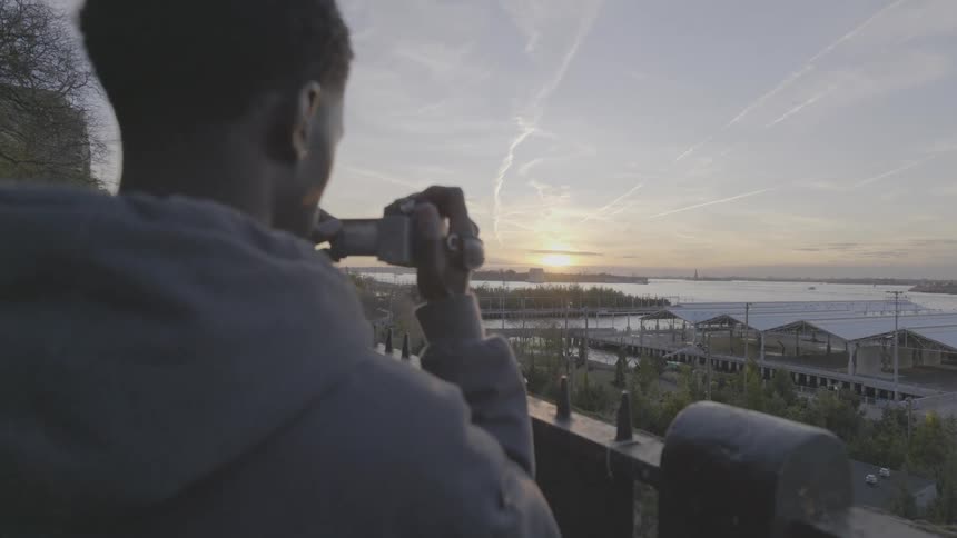 A teenager is filming the shore at sunrise