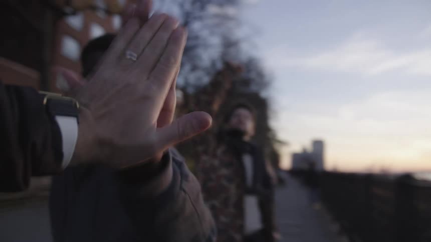 Closeup of friends sharing a high five in the city during fall at dusk