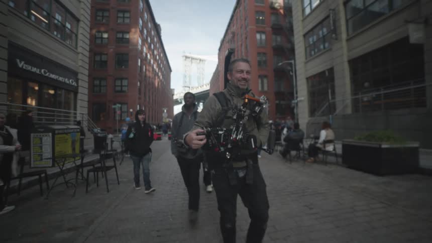 A film crew with cameras is walking down a city street