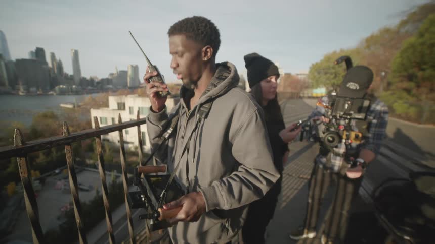 A film crew uses walkietalkies to communicate while setting up cameras on a city street