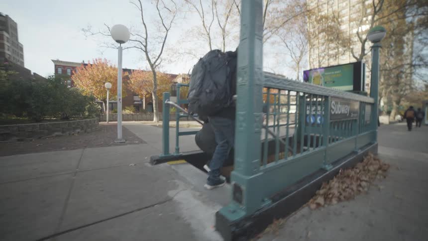 Two people dressed in thick winter clothing and carrying large backpacks walk into a subway station