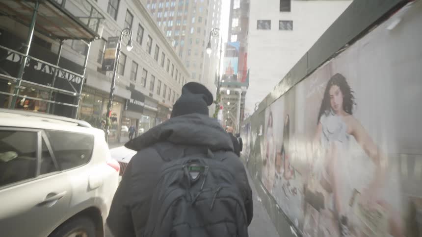 A man walks down the sidewalk downtown in a big city